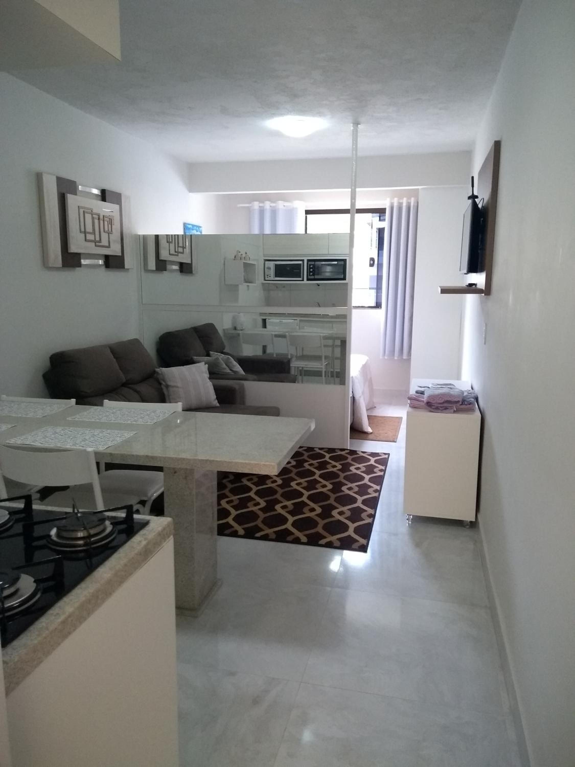 Cooktop em primeiro plano, mesa de granito e a sala do Apto 6 ao fundo