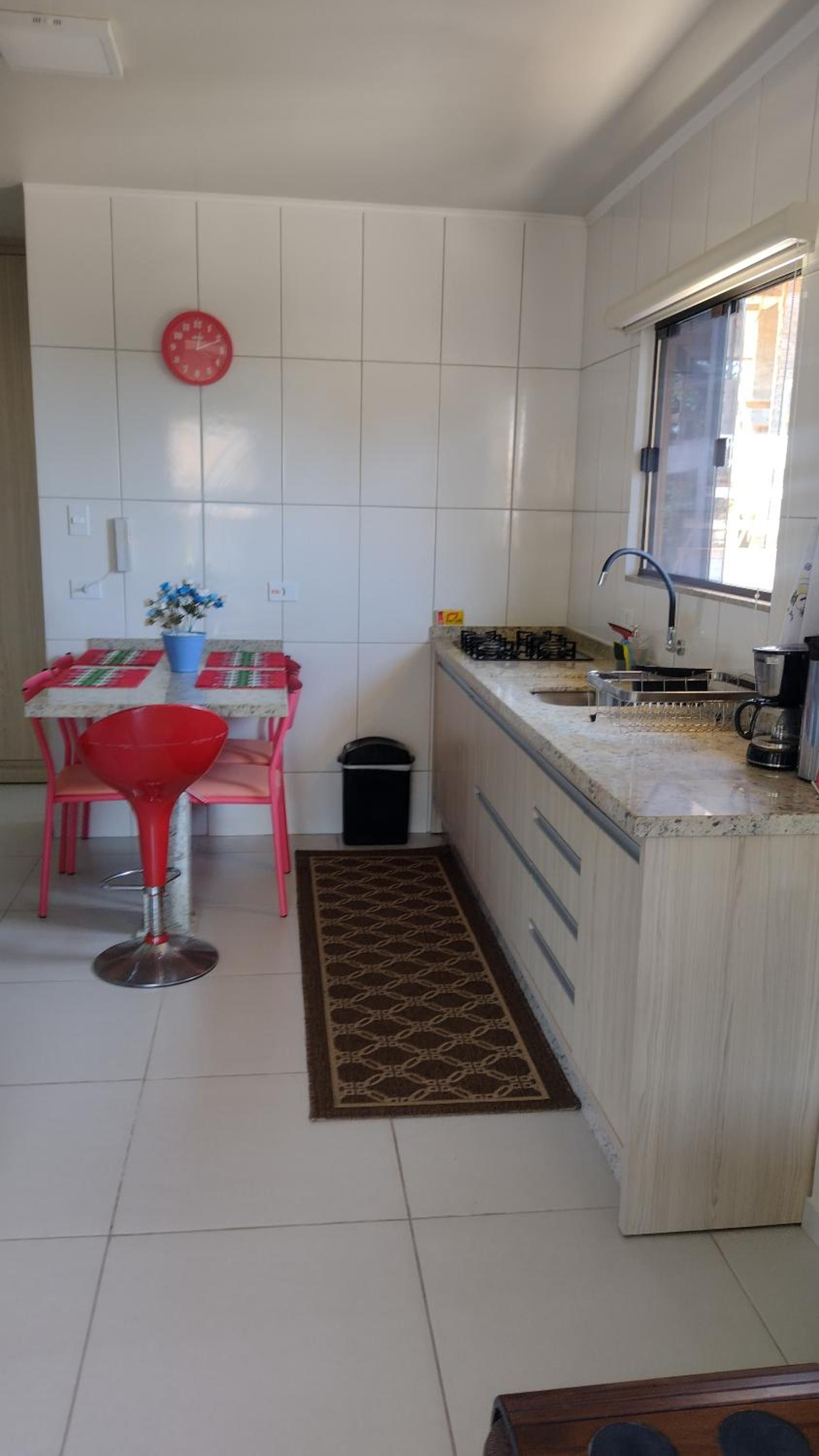 Cozinha em corredor do Apto 4, com bancada, cooktop e janela no fim